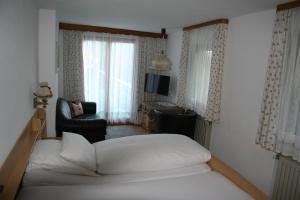 a bedroom with a bed and a chair and window at Gästehaus Sonnenbichl in Reit im Winkl