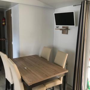 mesa de comedor con sillas y TV en la pared en DOMAINE DE KERLANN-MH6PERS-2CH-grande terrasse-tout confort en Pont-Aven