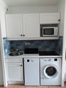 a kitchen with a washing machine and a microwave at Appartement T2 avec piscine a 100 m de la plage in Six-Fours-les-Plages