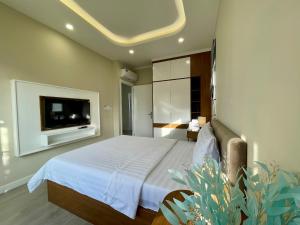 ein Schlafzimmer mit einem Bett und einem TV an der Wand in der Unterkunft WONDERLAND HỒ TRÀM in Bà Rịa