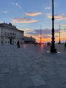 Un groupe de personnes marchant sur une place au coucher du soleil dans l'établissement Trieste Art Loft, à Trieste