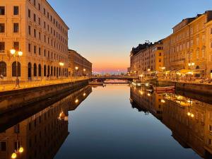 une rue de la ville avec des bâtiments et un canal la nuit dans l'établissement Trieste Art Loft, à Trieste