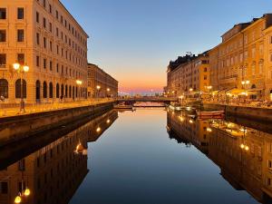 a city street with buildings and a canal at night at Trieste Art Loft in Trieste