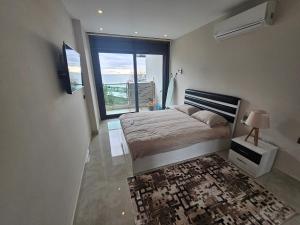een slaapkamer met een bed en een groot raam bij Konak Tower Seaside mahmutlar in Alanya