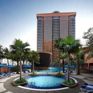 a hotel with a pool with palm trees and a tall building at Bukit Bintang Suite at Times Square KL in Kuala Lumpur