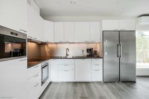 uma cozinha com armários brancos e um frigorífico de aço inoxidável em Uusi huvila Lahdessa em Lahti
