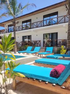 a row of blue lounge chairs in front of a resort at Sand Beach Boutique Hotel in Bwejuu