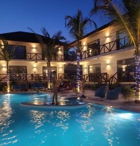 a person standing in front of a hotel at night at Sand Beach Boutique Hotel in Bwejuu