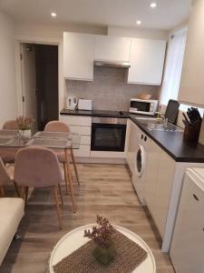 een keuken met witte kasten en een tafel en stoelen bij 2 Bedroom serviced apartment in Londen