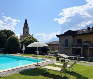 ein Pool mit Sonnenschirm und Stühlen neben einem Gebäude in der Unterkunft Residence Oleandro in Domaso