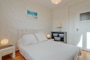 um quarto com uma cama com lençóis brancos e um candeeiro em Appartement Le Rial - Erquy em Erquy