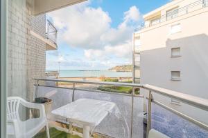 uma varanda com uma cadeira branca e vista para a praia em Appartement Le Rial - Erquy em Erquy