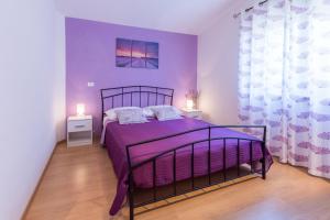 een slaapkamer met een paars bed en 2 nachtkastjes bij Villa Natali with private pool and kids playground near Fažana in Galižana