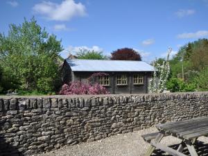 a stone wall next to a wooden bench and a building at 1 Bed in Bourton-on-the-Water 44961 in Withington
