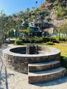 a stone fire pit with a bench in a park at Green Lodge Farmstay by Highland Monk in Shimla