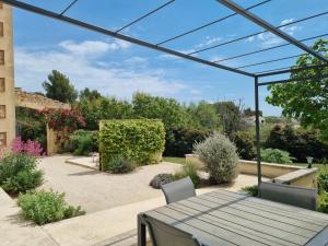 a patio with a table and chairs and plants at Les Garrigues de la Vallée des Baux in Paradou