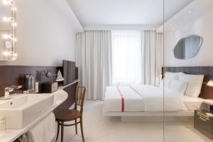 - une chambre blanche avec un lit et un lavabo dans l'établissement Ruby Hanna Hotel Stuttgart, à Stuttgart