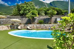 a pool in a yard with two chairs and an umbrella at Luxury Apartment Val di Monte in Malcesine