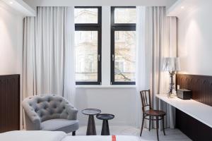 a bedroom with a bed and a chair and windows at Ruby Hanna Hotel Stuttgart in Stuttgart