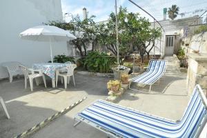 - une terrasse avec 2 chaises, une table et un parasol dans l'établissement Appartamento Zii Mpeu by Salentoaffitti, à Racale