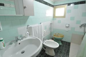 La salle de bains est pourvue d'un lavabo blanc et de toilettes. dans l'établissement Appartamento Zii Mpeu by Salentoaffitti, à Racale