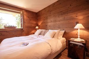 a bedroom with a white bed with a wooden wall at Chalet with a beautiful view on the heights of in Verbier