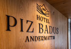 een bord voor een hotel genaamd babus andarine op een houten muur bij Hotel Piz Badus in Andermatt
