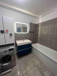 a bathroom with a tub and a sink and a washing machine at Appartement adorable et jardin in Villiers-sur-Marne