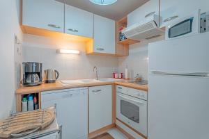 a kitchen with white cabinets and a refrigerator at Appartement Les Bains - Erquy in Erquy