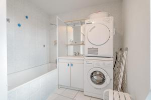 ein weißes Badezimmer mit einer Waschmaschine und einer Badewanne in der Unterkunft Appartement Les Bains - Erquy in Erquy