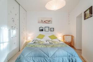 a bedroom with a blue bed in a white room at Appartement Les Bains - Erquy in Erquy