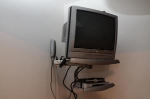 un monitor de ordenador en una estantería con un sistema de videojuegos en Apartments Karlin, en Praga