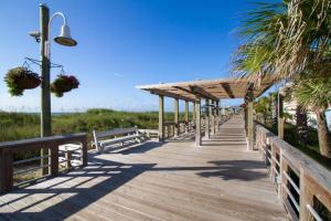 eine hölzerne Promenade, die zum Strand mit Bänken führt in der Unterkunft Blue Heron Nest in Carolina Beach
