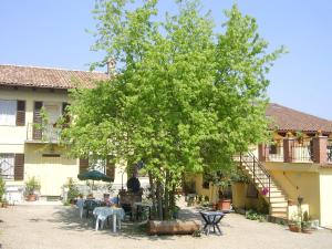 een grote boom voor een gebouw met tafels bij Il Girasole in Mombaruzzo