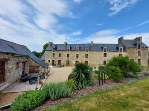 a large stone building with a patio in front of it at Chambres d'Hôtes La Rompardais in Pléven