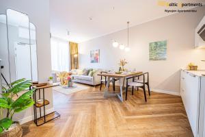 a kitchen and living room with a table and a couch at Baltic Apartments - Seaside Garden Apartments & Wellness in Świnoujście