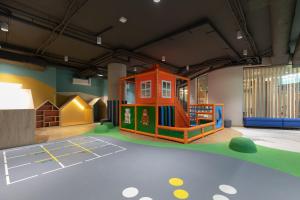uma sala para crianças com um conjunto de jogos e um parque infantil em Gryfa Pomorskiego Sea View Apartment with parking by Rent like home em Międzyzdroje