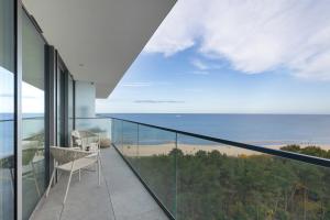 uma varanda com uma cadeira e vista para o oceano em Gryfa Pomorskiego Sea View Apartment with parking by Rent like home em Międzyzdroje