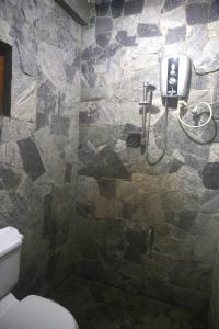 uma casa de banho com um chuveiro e uma parede de pedra em The Dream Inn em Ella