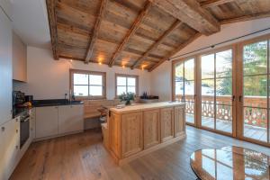 eine Küche mit Holzdecken, Fenstern und einem Tisch in der Unterkunft Chalet Marmotta CULM - Luxus Chalet Ski-In Ski-Out in Sankt Anton am Arlberg