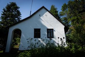 una iglesia blanca con techo negro en Százéves ház - Vérteskozma 48, en Gánt
