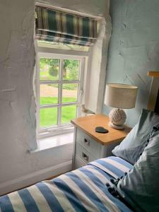 a bedroom with a bed and a desk with a window at Grooms cottage, a tranquil Cornish retreat in Lanteglos