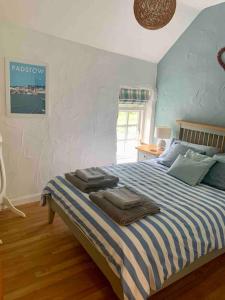 1 dormitorio con 1 cama con toallas en Grooms cottage, a tranquil Cornish retreat en Lanteglos