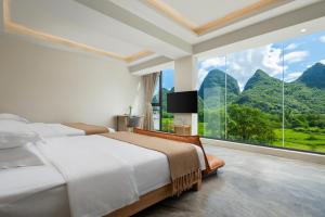a bedroom with two beds and a large window at Dreamland Inn in Yangshuo