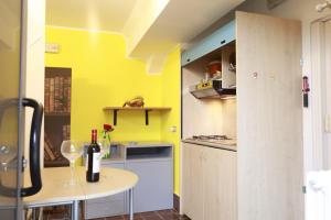 Lo studio di Podere Bellavista في مونتيبراندون: مطبخ بجدران صفراء وطاولة مع زجاجة نبيذ