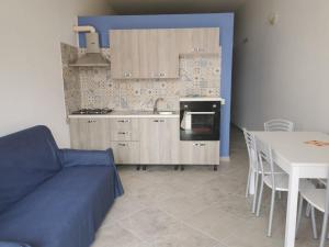 Residence Fortunato في بوليكاسترو بوسينتينو: مطبخ مع أريكة زرقاء وطاولة ومطبخ مع غرفة طعام