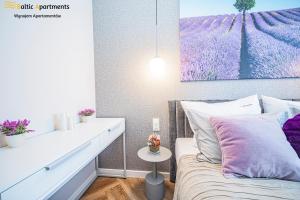 a bedroom with a bed and a table and a painting at Baltic Apartments - Seaside Garden Apartments & Wellness in Świnoujście