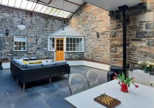 patio con sofá, mesas y pared de ladrillo en The Manor Criccieth, en Porthmadog