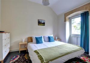 Un dormitorio con una cama con almohadas azules y una ventana en The Manor Criccieth, en Porthmadog