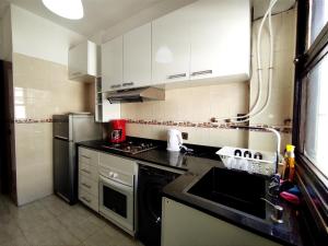 a kitchen with white cabinets and a black counter top at rabatapartmentresidence in Rabat